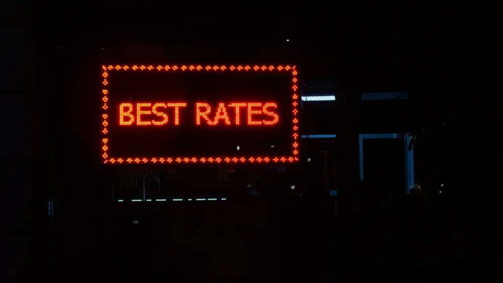 Neon Best Rates sign glowing in a dark London street shop window
