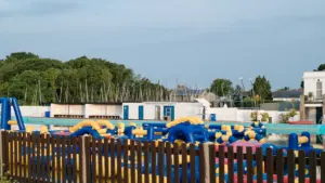 Blue and yellow inflatable pool obstacle course behind a wooden fence outdoors
