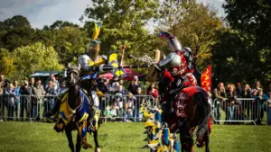 Two armored knights on horseback collide while jousting during a historical outdoor reenactment event.