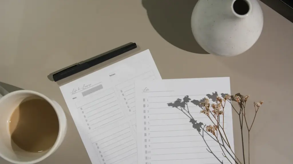 Top-down view of a planner, pen, coffee mug, and dried flowers on desk.