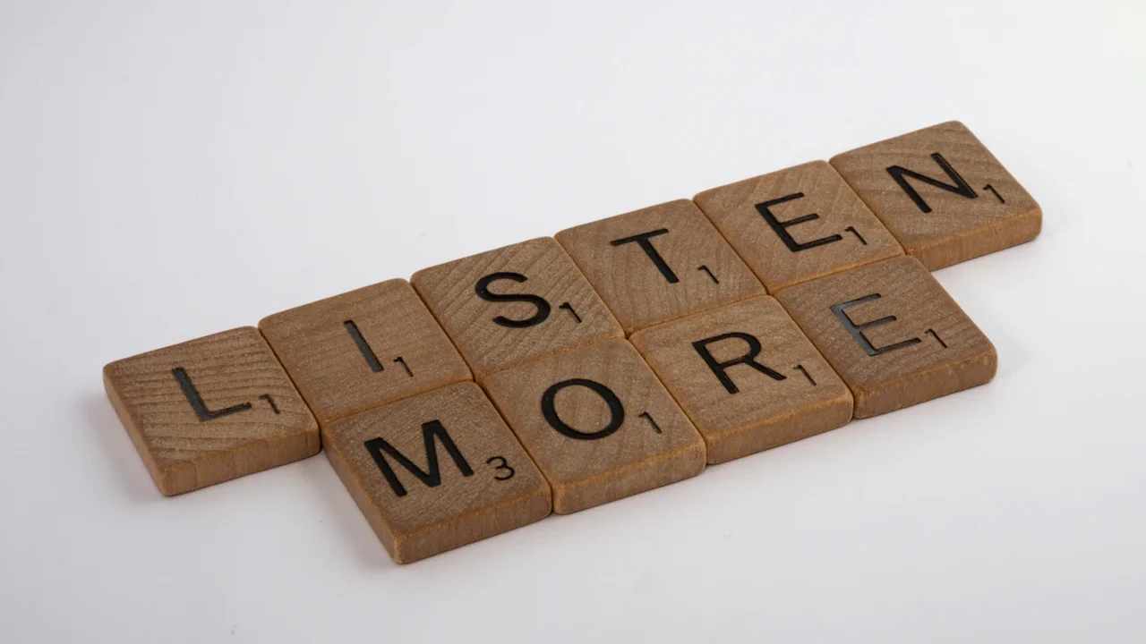 Scrabble tiles on a white background spelling out the phrase Listen More.